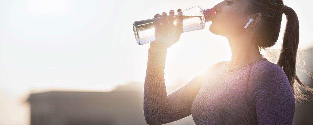 Donna che sta correndo che si ferma per bere acqua