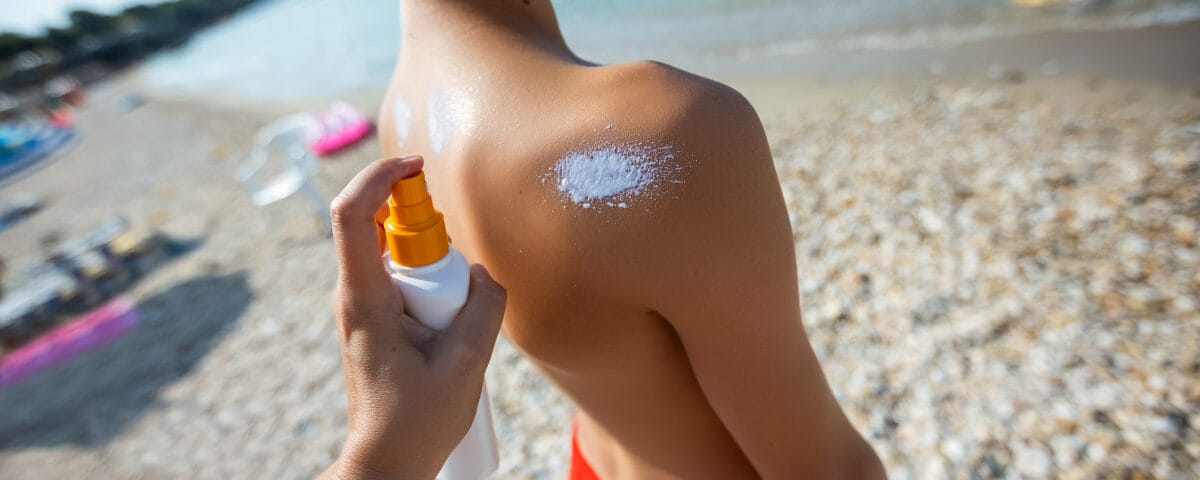 Crema solare spruzzata sulla spalla di un bambino in spiaggia