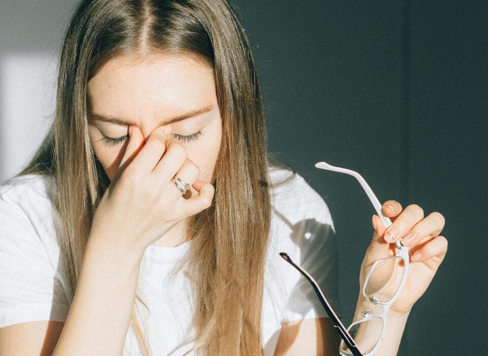 Ragazza che si toglie gli occhiali e si tocca gli occhi per stanchezza